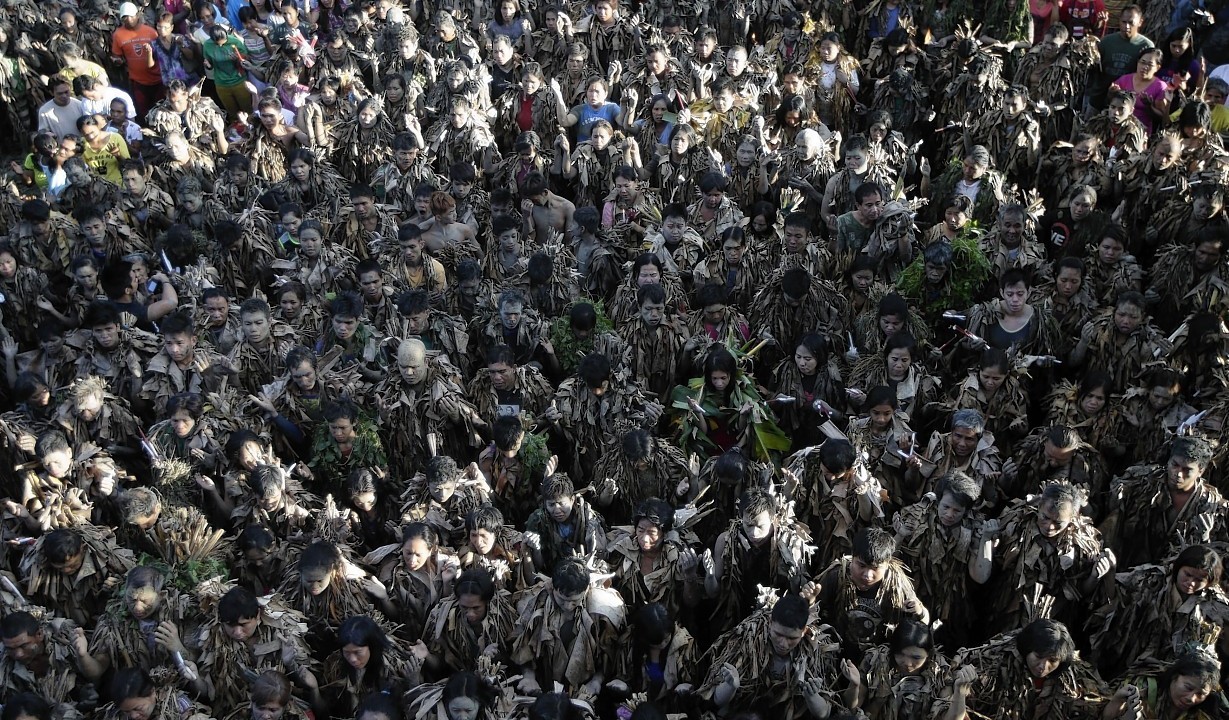 Residents, with their faces covered with mud and donning mostly dried Banana leaves, attend a mass to celebrate the Feast Day of St. John the Baptist at the village of Bibiclat, Aliaga township, Nueva Ecija province in northern Philippines