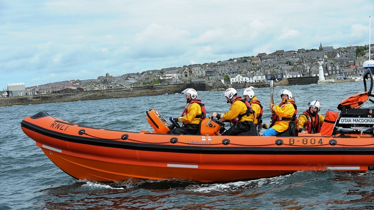 The Glasgow 2014  Commonwealth Games Queens Baton Relay.
Batonbearer Kay Copland carrying the Queen's Baton from Banff harbour to Macduff harbour by Lifeboat.