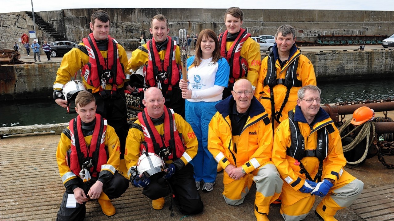 The Glasgow 2014  Commonwealth Games Queens Baton Relay.
Batonbearer Kay Copland carrying the Queen's Baton from Banff harbour to Macduff harbour by Lifeboat.