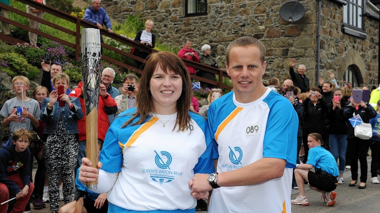 The Glasgow 2014  Commonwealth Games Queens Baton Relay.
Batonbearers Kay Copland and Dennis Chalmers  carrying the Queen's Baton at Banff harbour.