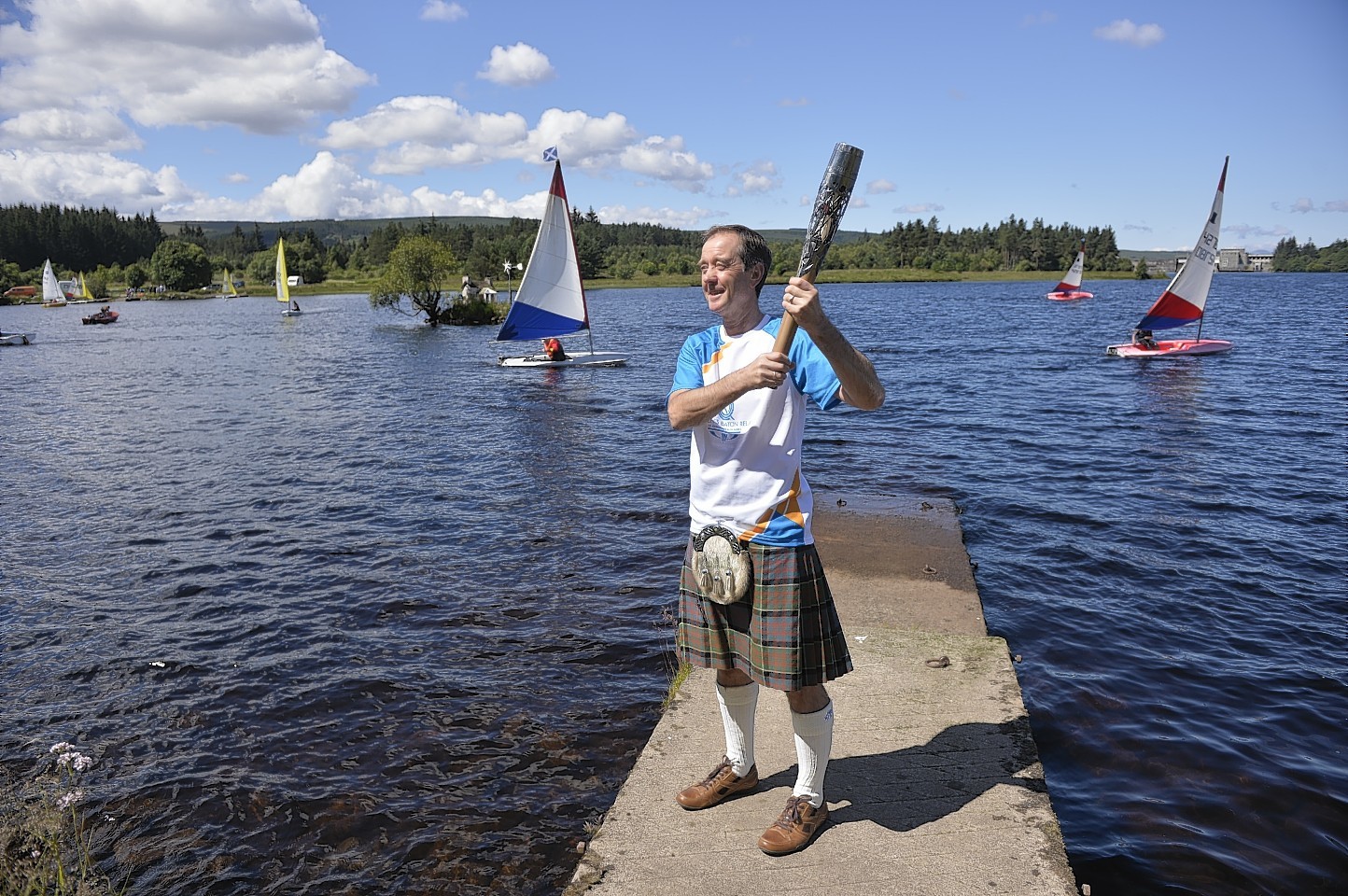 Thomas Mathieson carrying the Glasgow 2014 Queen's Baton through Lairg in the Scottish Highlands.