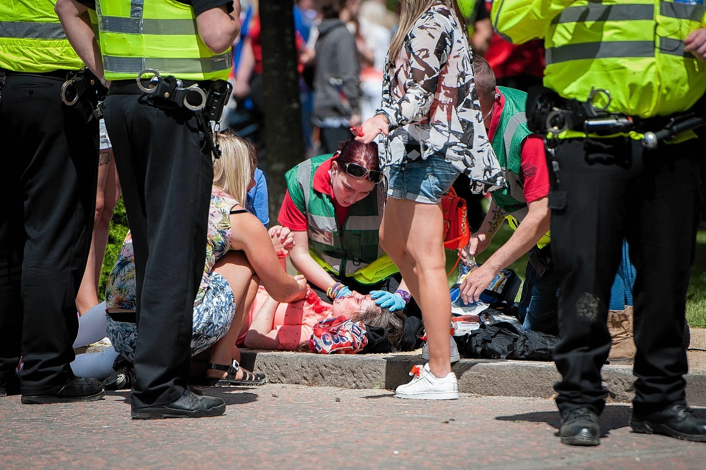 The girl is tended to as she lies on the ground after being hit by a bottle thrown during the parade