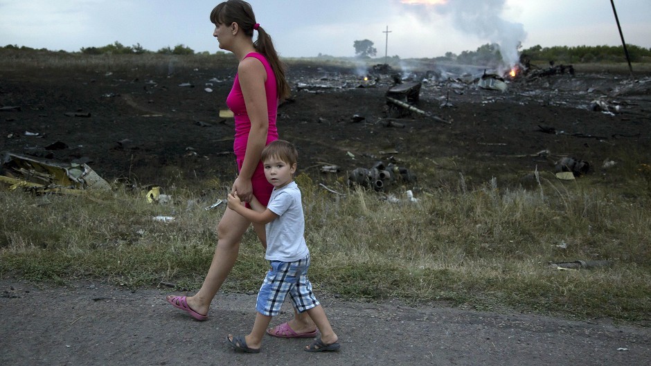 A woman with a child walks past the crash site (AP)