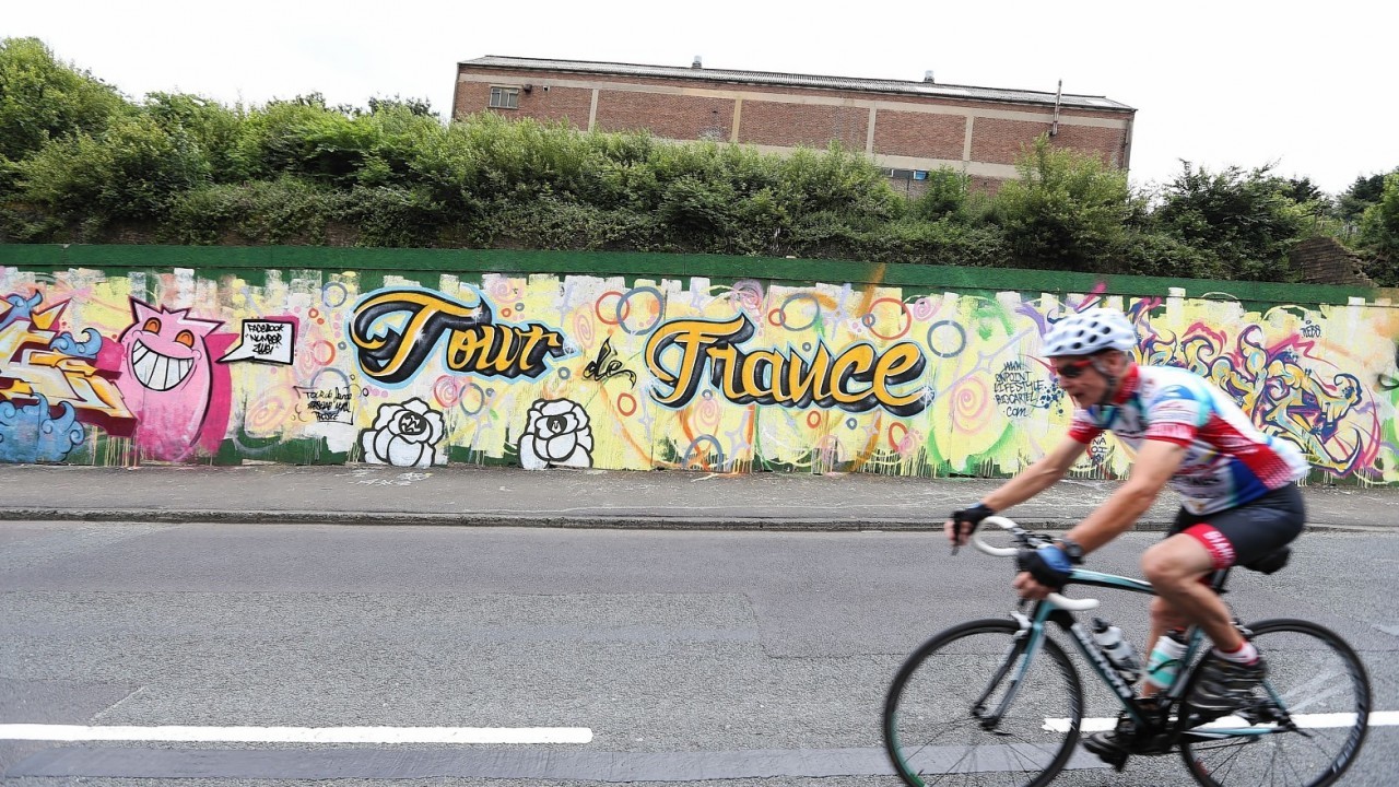 A cyclist passes a Tour de France mural in Greetland, near Ripponden, Yourkshire