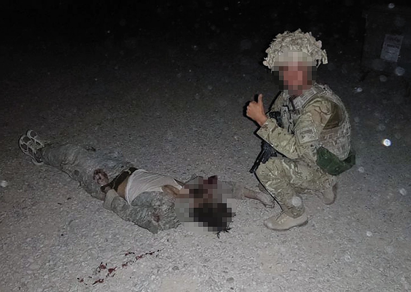 A soldier poses with a dead body in Afghanistan