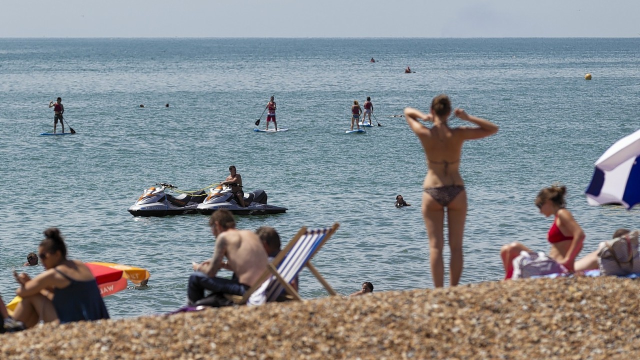 People flock to the beach in Brighton, East Sussex as temperatures soar across the country