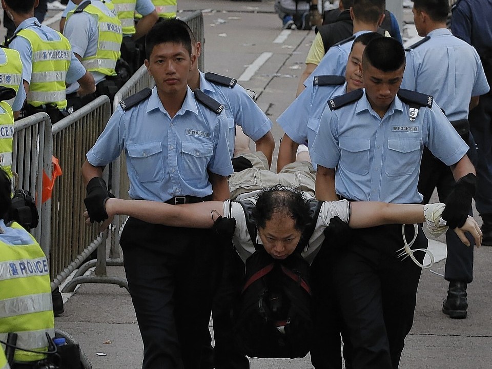 Protesters are taken away by police officers after hundreds of protesters staged a peaceful sit-ins overnight on a street in the financial district in Hong Kong Wednesday, July 2, 2014