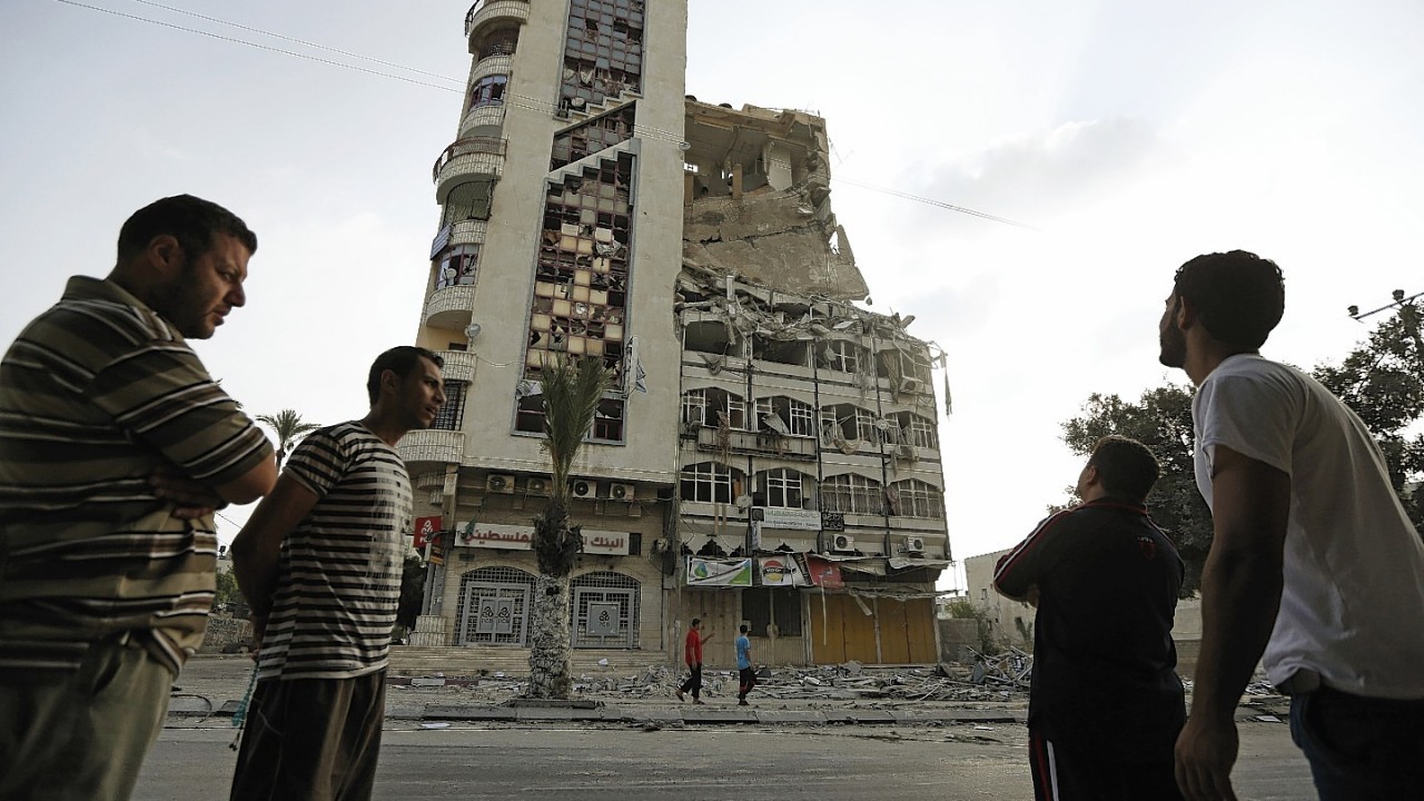 Palestinians inspect the damage of the Al-Shalam (Peace) tower, destroyed by an overnight Israeli strike, in Gaza City, Tuesday, July 22, 2014