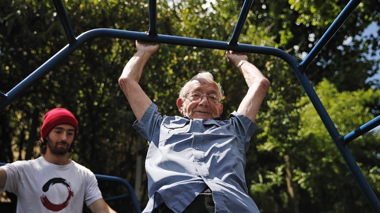 George Jackson, 85, an army veteran and former boxer swings on monkey bars as he participates at a parkour class for elderly people at a park in south London