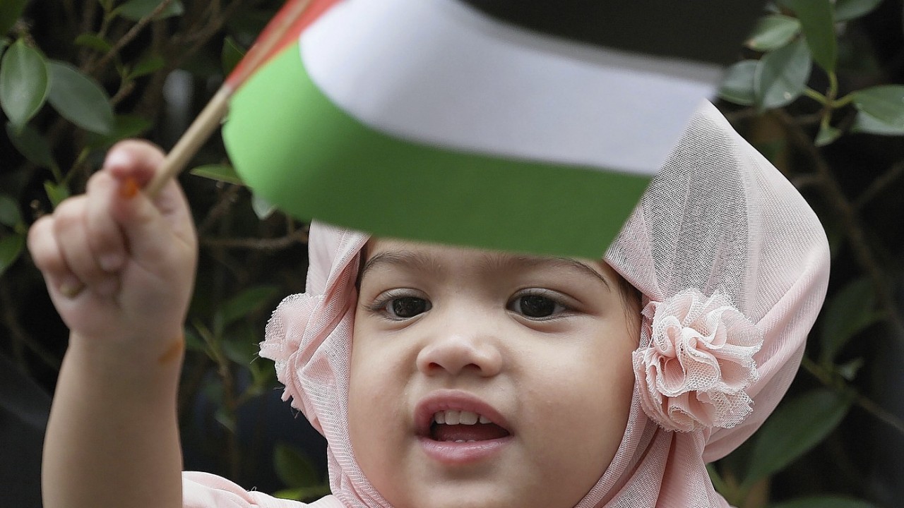 A Thai-Muslim girl waves a small Palestinian flag as her parents attend a rally outside the Israeli embassy in Bangkok. Several hundreds of activists took part in the rally to show solidarity for Palestine against Israel's attacks on Gaza