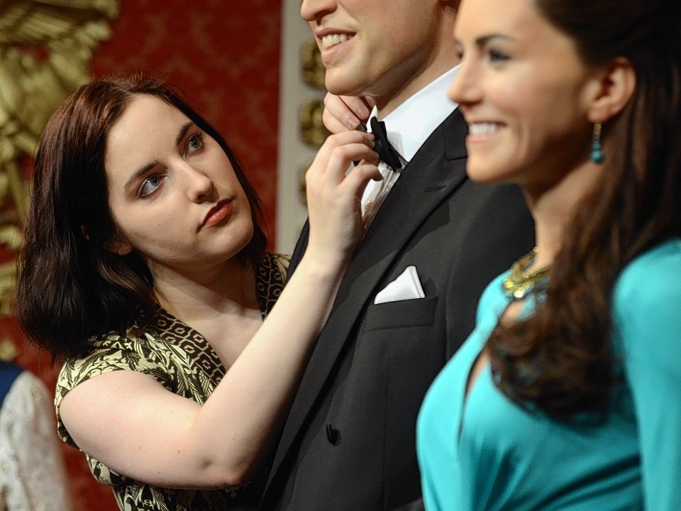 Wardrobe assistant Luisa Compobassi applies finishing touches to the wax figures of the Duke and Duchess of Cambridge as they are unveiled at Madame Tussauds, London.