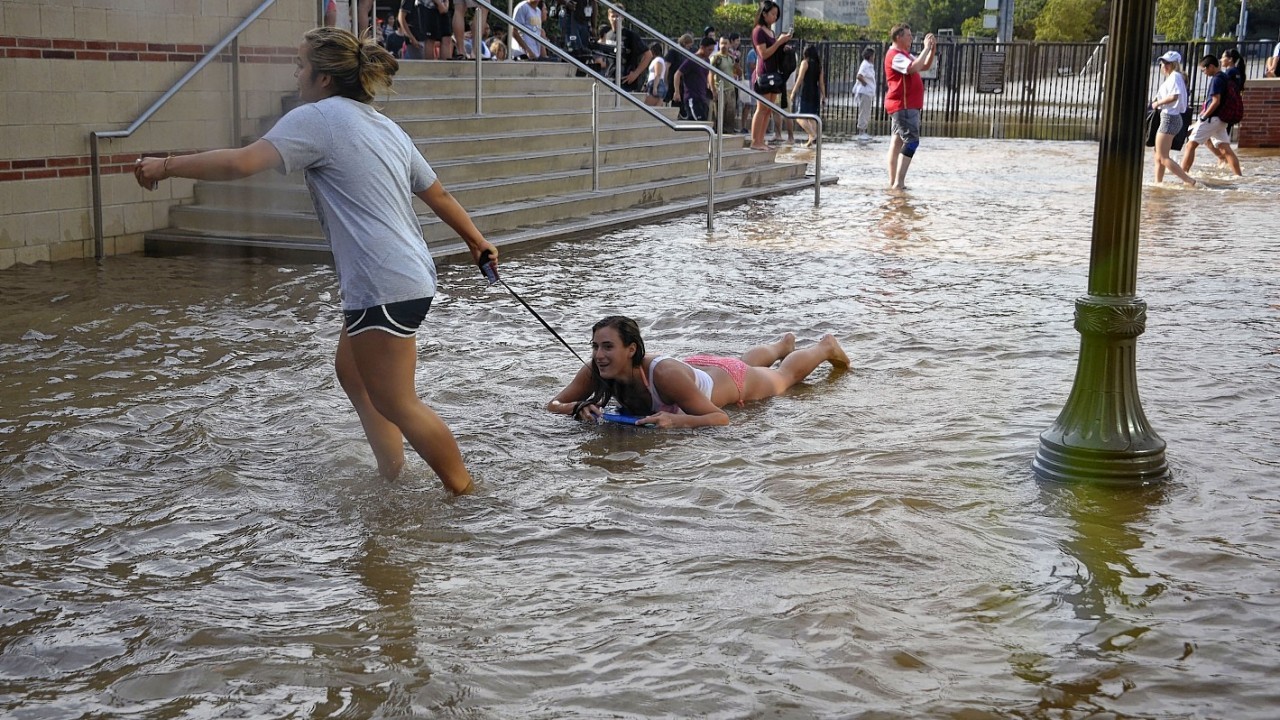One woman pulls another on a body board through water on the quad of UCLA after flooding from a broken 30-inch water main under nearby Sunset Boulevard inundated a large area of the campus in the Westwood section of Los Angeles