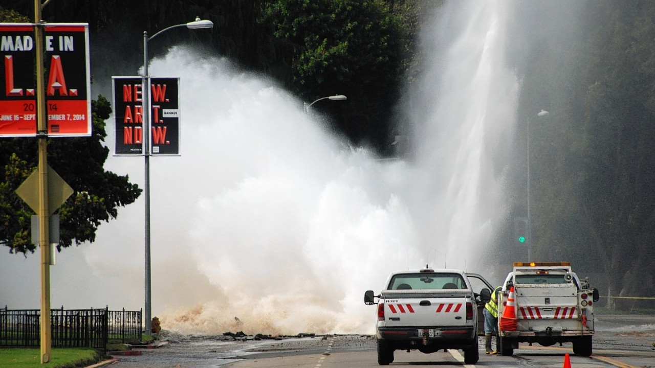Water shoots in the air from a broken 30-inch water main under Sunset Boulevard, uphill from UCLA in the Westwood section of Los Angeles