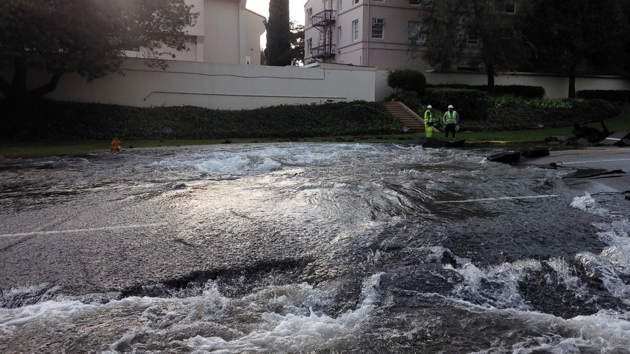 Water floods the street after a 30-inch water main burst on Sunset Boulevard near UCLA in the Westwood section of Los Angeles