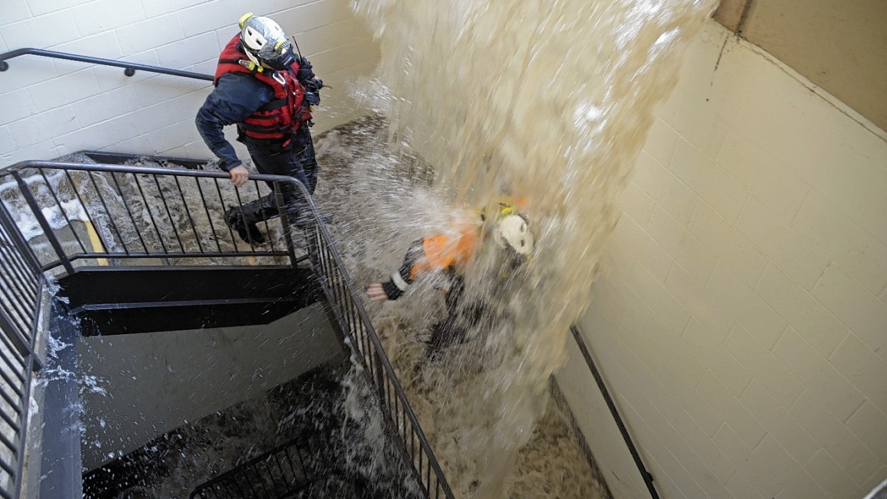 Workers walk down stairs to a parking structure as water cascades down on them on the UCLA campus after flooding from a broken 30-inch water main under nearby Sunset Boulevard inundated a large area of the campus in the Westwood section of Los Angeles