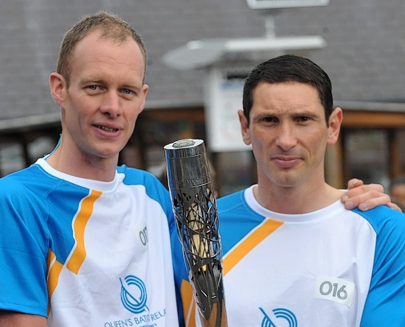 David Smith (left) carrying the baton with shinty star Ronald Ross in Aviemore