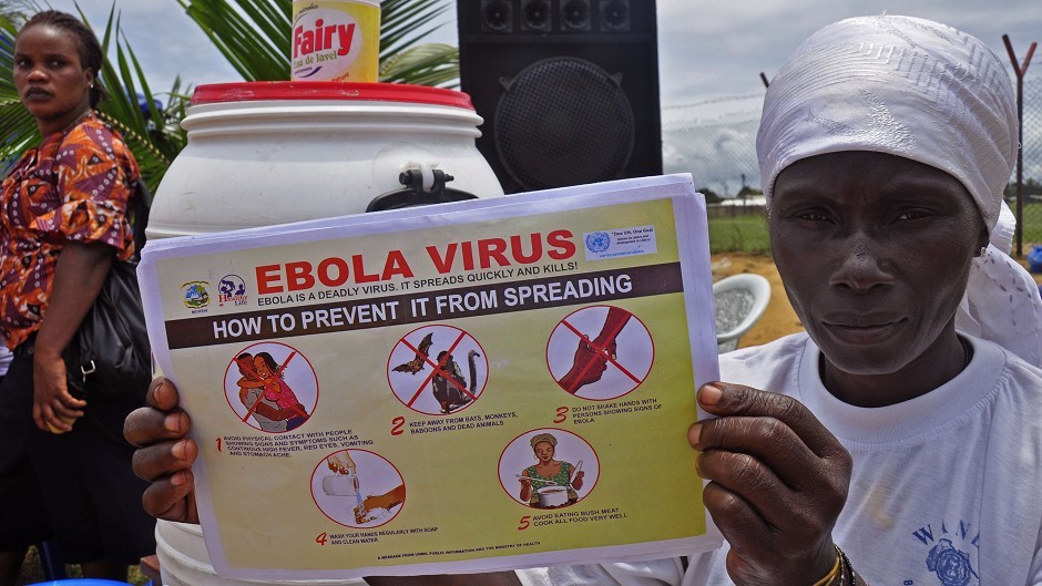 A Liberian woman holds up a pamphlet with guidance on how to prevent the Ebola virus from spreading, in the city of Monrovia (AP)