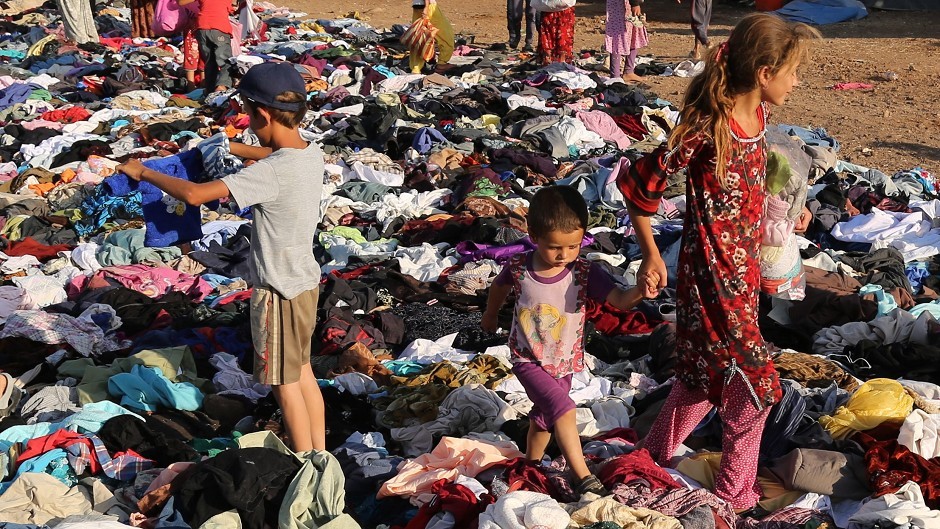 Displaced Iraqis from the Yazidi community look for clothes to wear among items provided by a charity at the Nowruz camp in Derike, Syria (AP)