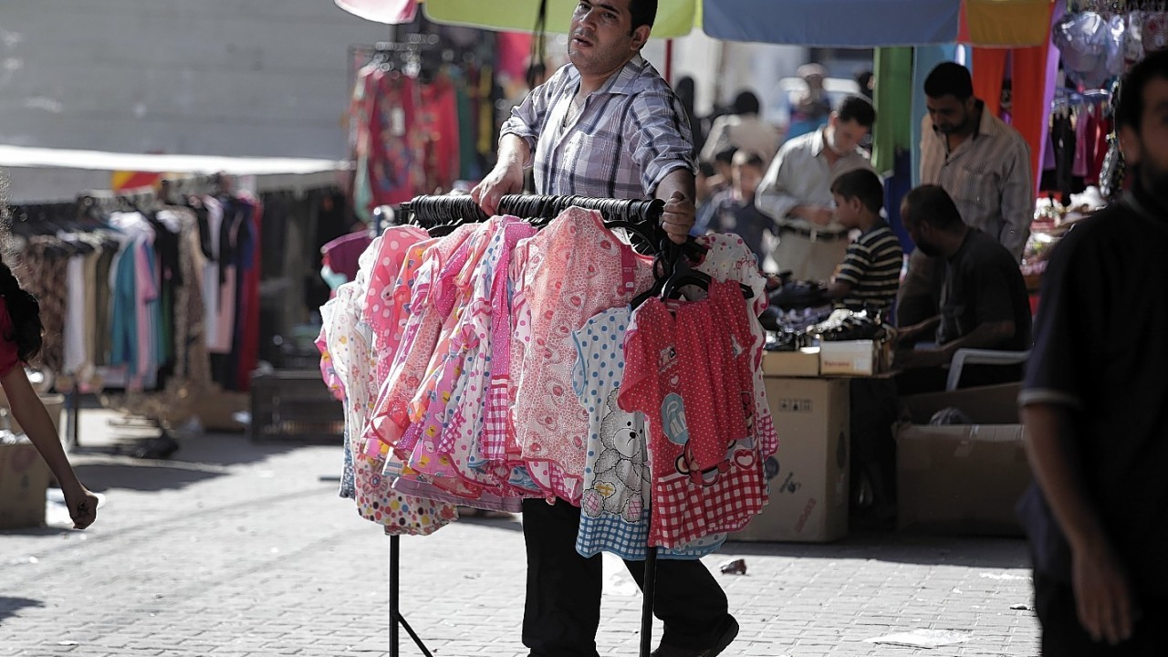 A shop owner carries merchandise outside his shop at a market in Gaza City, northern Gaza Strip, Wednesday, Aug. 6, 2014.