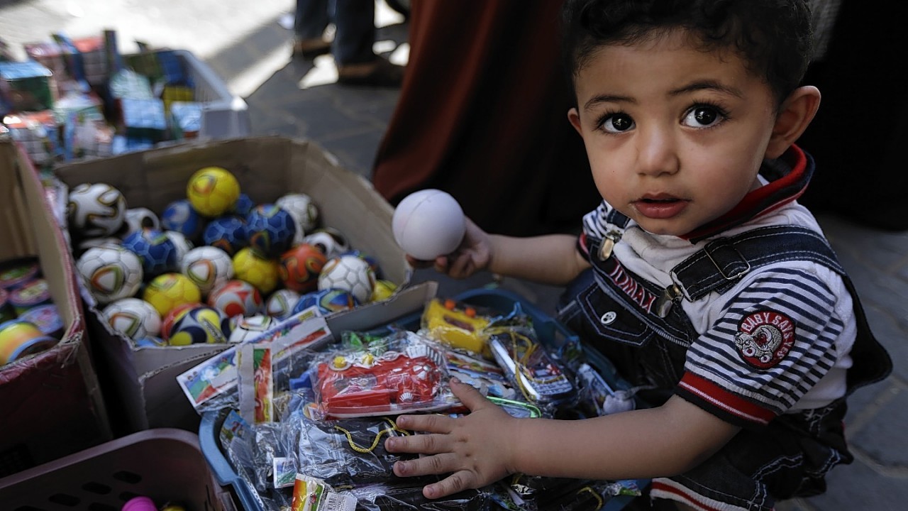 A Palestinian child goes through toys at a vendor's stall in a market in Gaza City, northern Gaza Strip, Wednesday, Aug. 6, 2014.