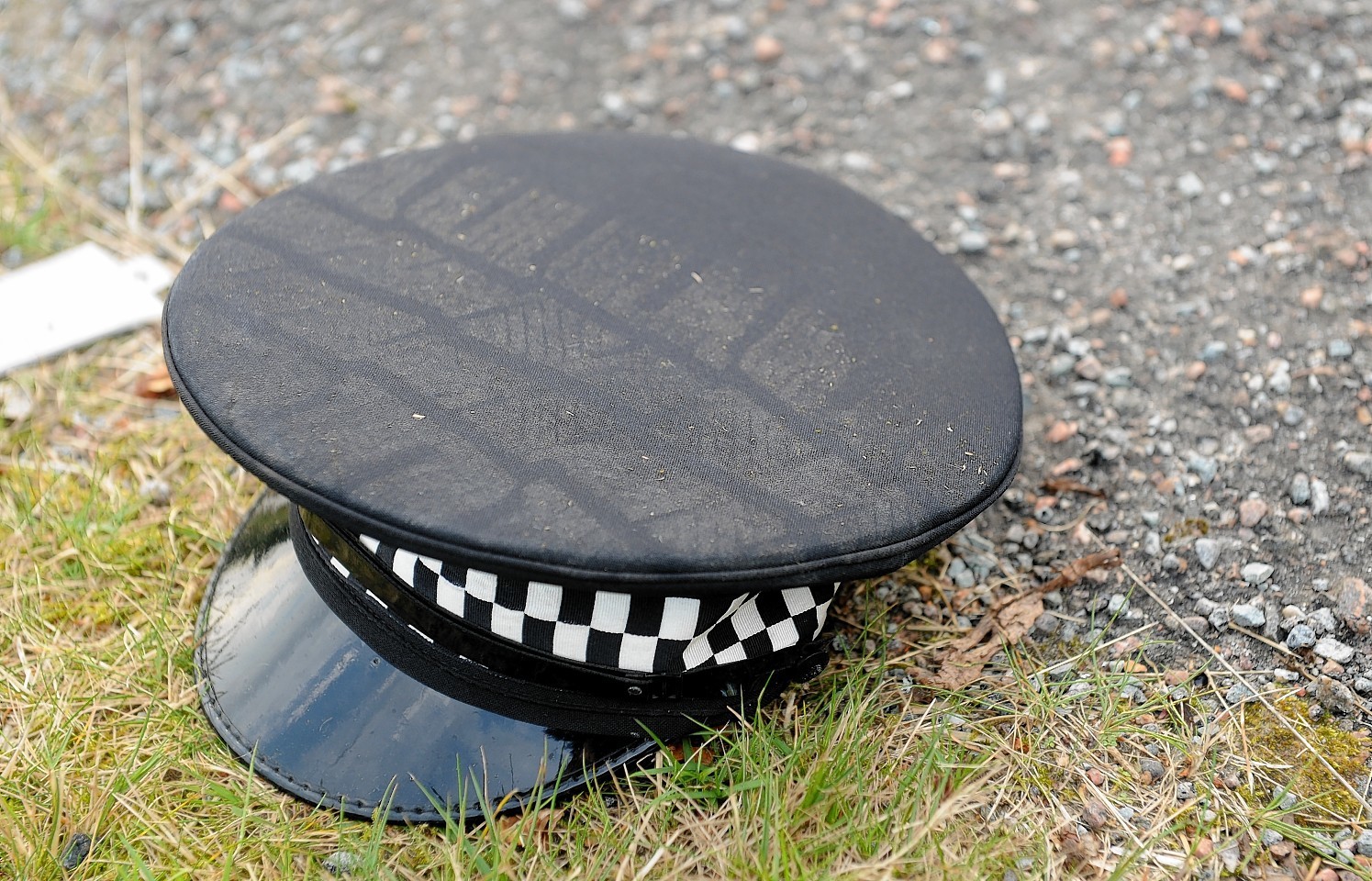 A police hat with tyre marks over it at the scene
