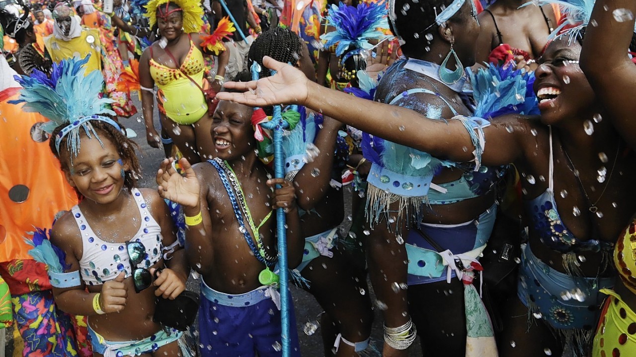 Young dancers laugh as they are showered with ice water during the West Indian Day Parade, Monday, Sept. 1, 2014 in the Brooklyn borough of New York