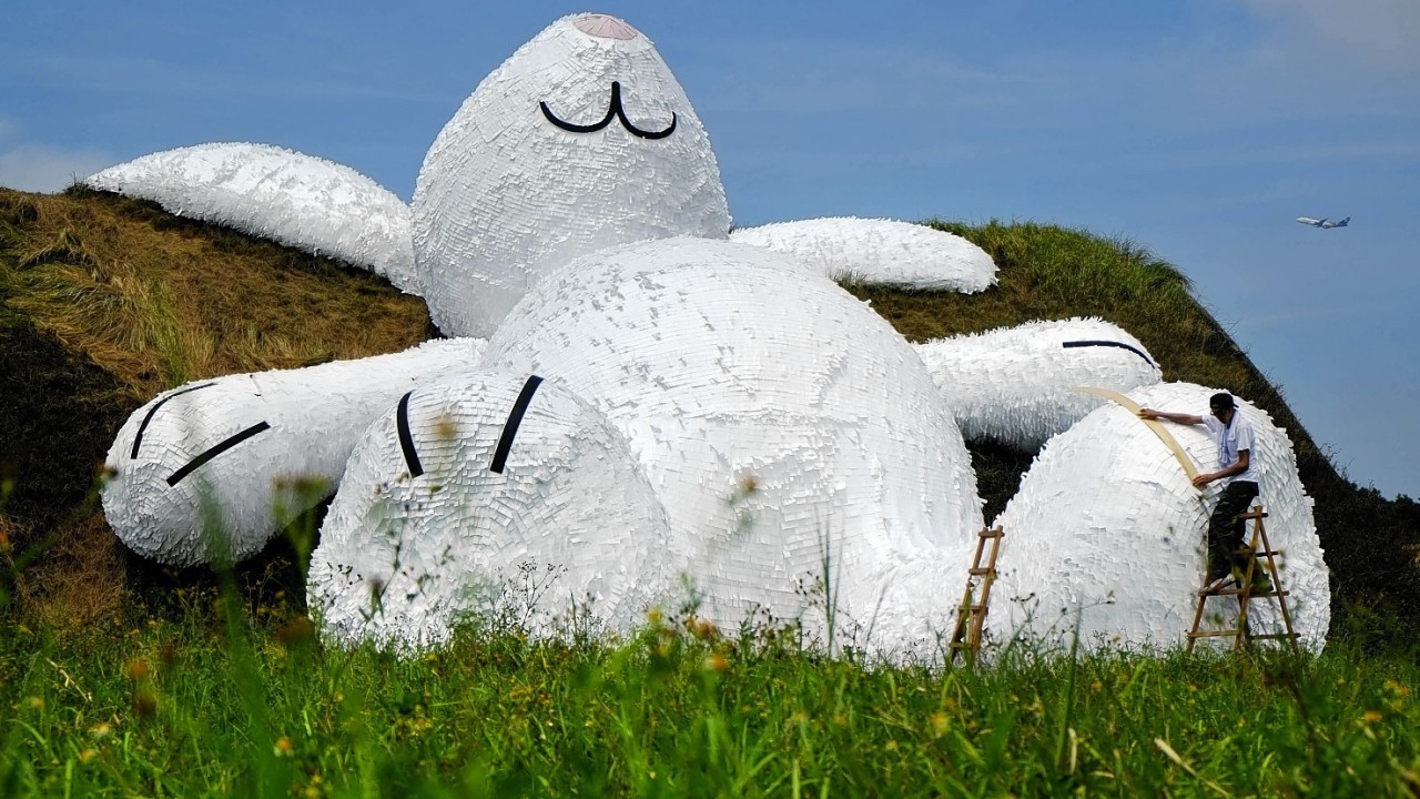 Dutch artist Florentijn Hofman's latest creation, a 25 meters (82 feets) white rabbit, leans up against an old aircraft hangar as part of the Taoyuan Land Art Festival in Taoyuan, Taiwan, Tuesday, Sept. 2, 2014