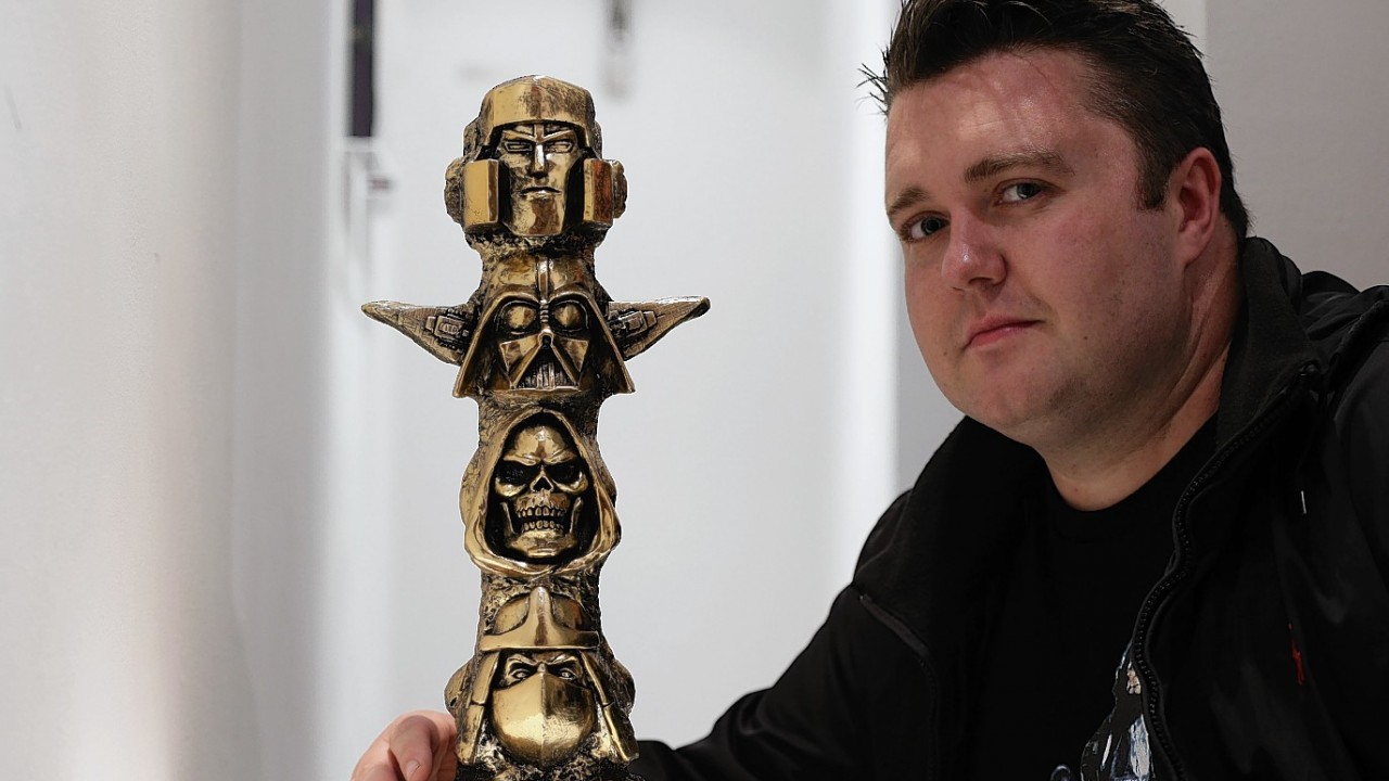 Artist Ryan Callanan, also known as RYCA, poses next to his piece Toy Totem 1 (Gold), during a preview for his exhibition 8 Forever, at Lawrence Alkin Gallery in London