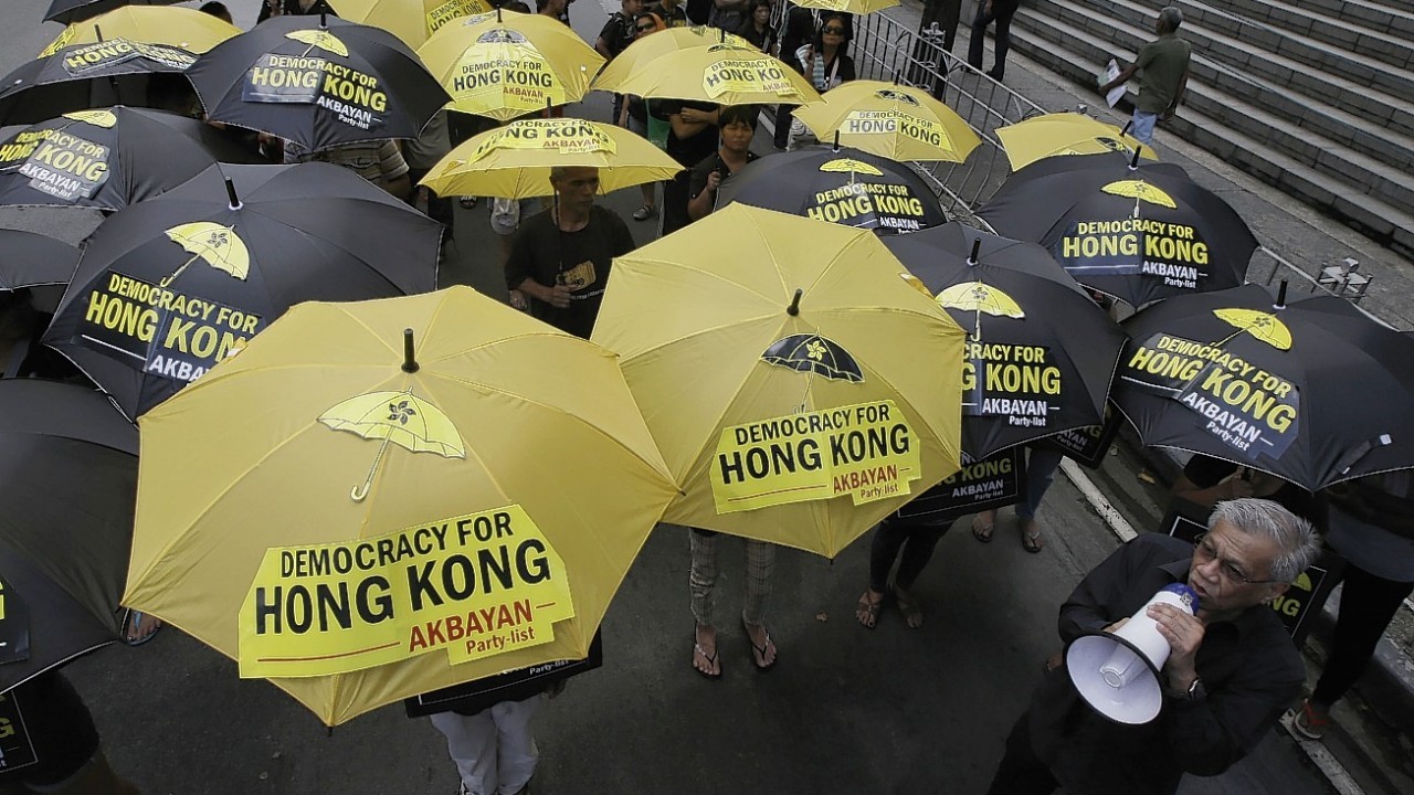 Protesters, led by Congressman Walden Bello, bottom right, open their yellow and black umbrellas outside the Chinese Consulate at the financial district of Makati city east of Manila, Philippines