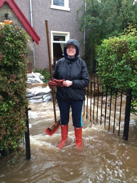 Evie Lumsden tries to keep flood waters from her mother's home on Millburn Road