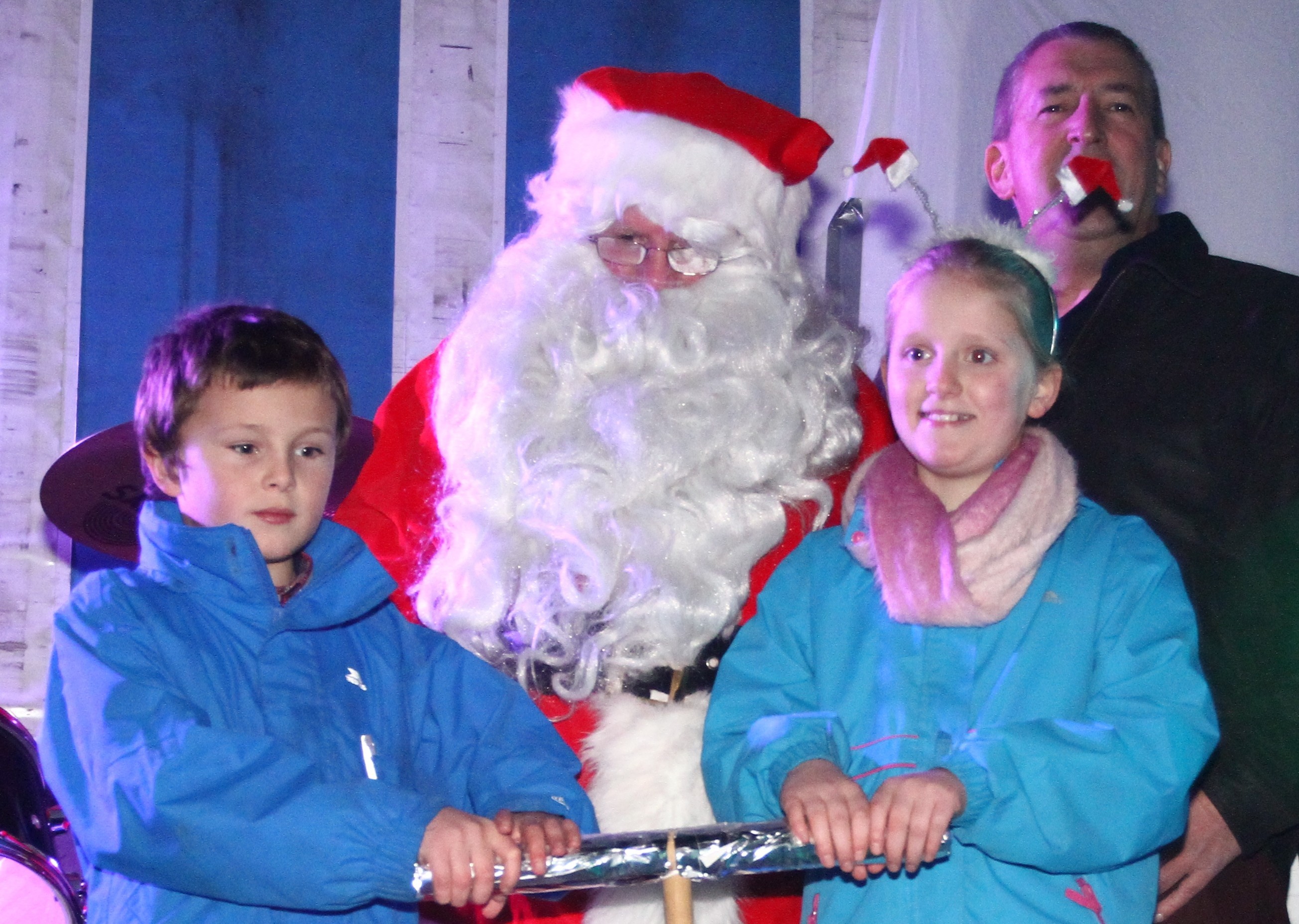 Santa keeps an eye on Logan Watson (left) and Iona Keyes with Graeme Bass Chair of Bid4Oban as they push the plunger to switch on the Christmas lights in Oban as part of the Reindeer Parade.