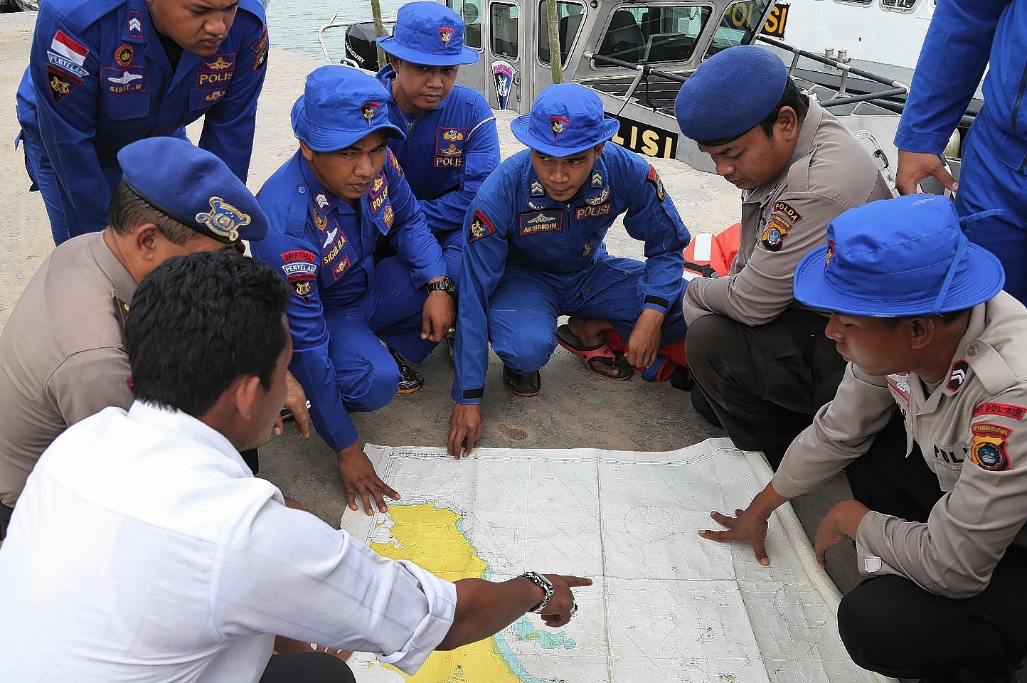 Members of Indonesia's Marine Police hold a briefing on board a search and rescue craft prior to their heading out to sea to search for the missing AirAsia flight QZ8501