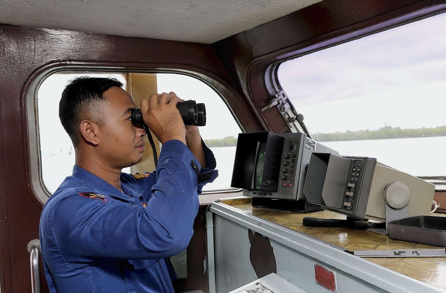 An Indonesian Marine Policeman checks his surroundings from his search and rescue crafts as he and his crew members prepare a search operation for the missing AirAsia flight QZ8501