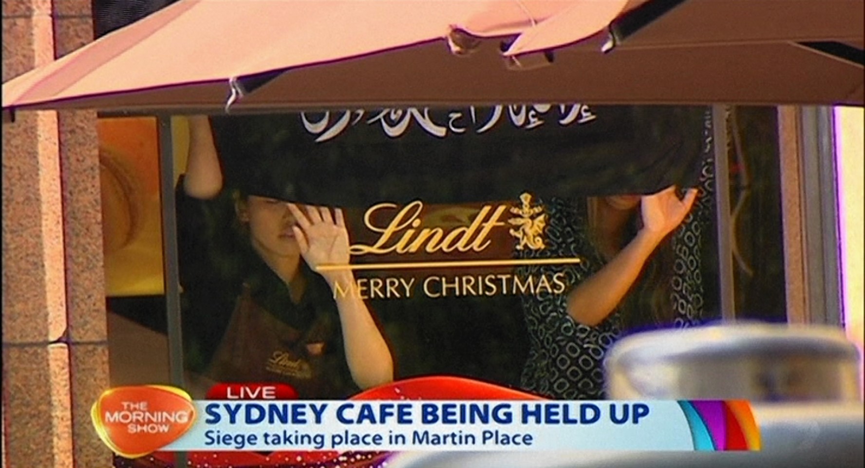 Hostages hold up an Islamic flag at the Sydney cafe