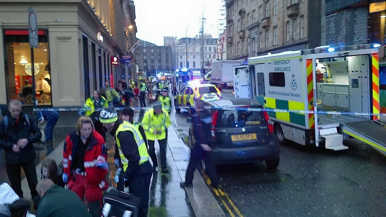 A police officer at the scene of the bin lorry crash in Glasgow. The lorry can be seen in the background.
