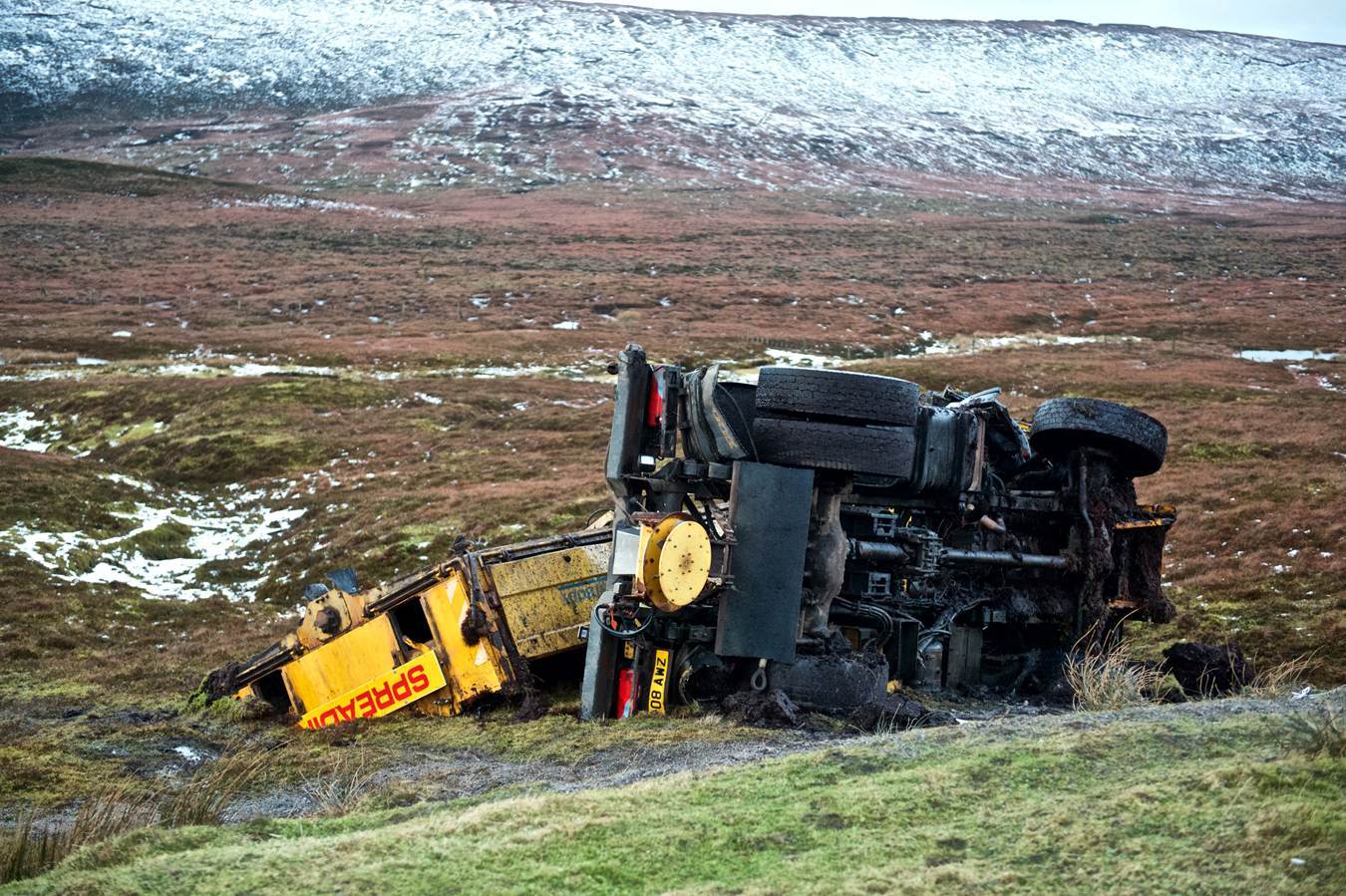 The overturned gritter lying beside the road