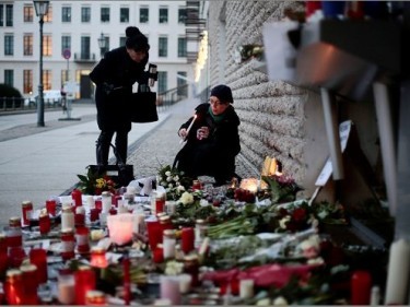 Women light candles to commemorate the victims killed in an attack at the Paris offices of the weekly newspaper Charlie Hebdo, in front of the French Embassy in Berlin, 