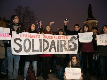  Parisians hold a poster saying 'Students, Journalists, United' as crowds gather at 'Place de la Republique' in solidarity