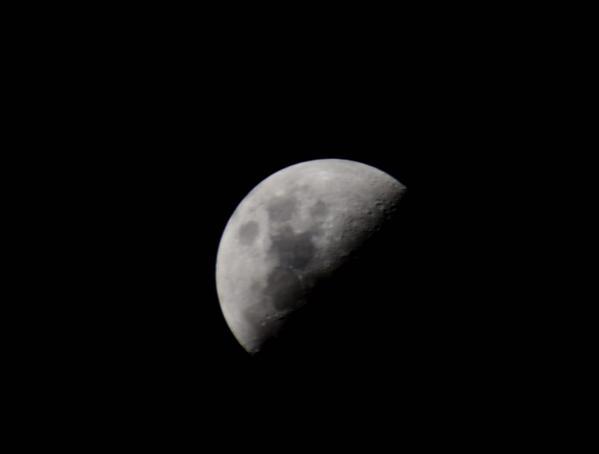 An image of the moon, half-shrouded in the darkness of space, from the ISS