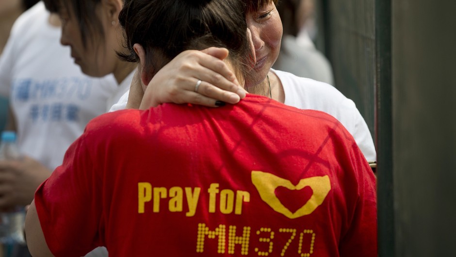 Chinese relatives of passengers on board the missing Malaysia Airlines MH370 plane cry during a protest at the Malaysian embassy in Beijing (AP)