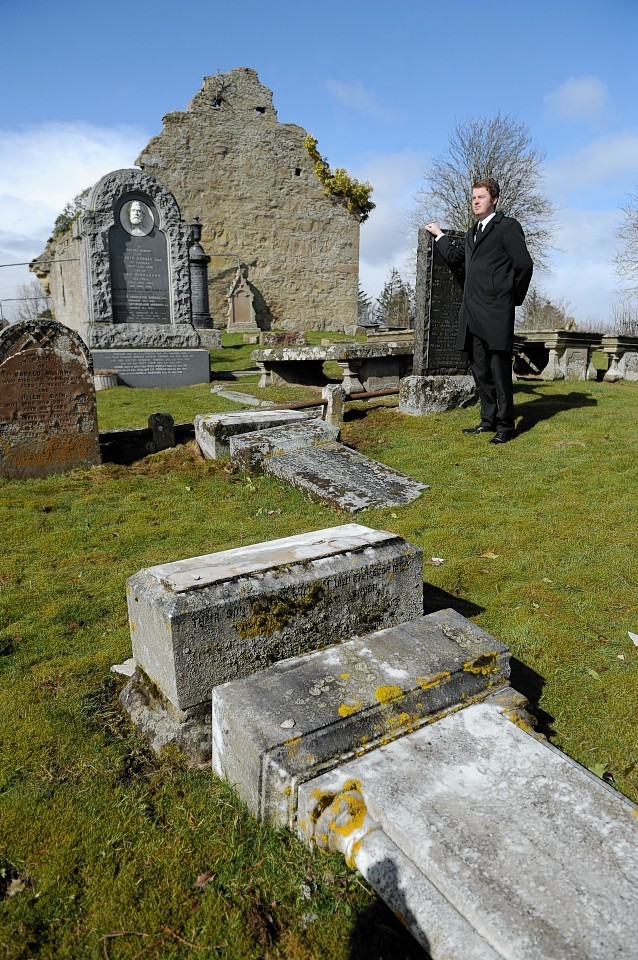 Undertaker Jack Rhind stands next to one of the toppled stones