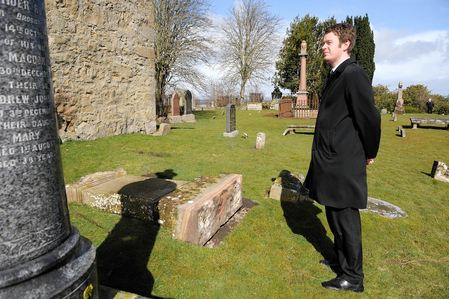 Undertaker Jack Rhind stands next to one of the toppled stones