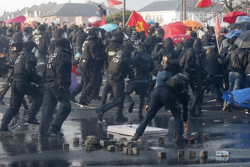 Police chase demonstrators after they threw stones 