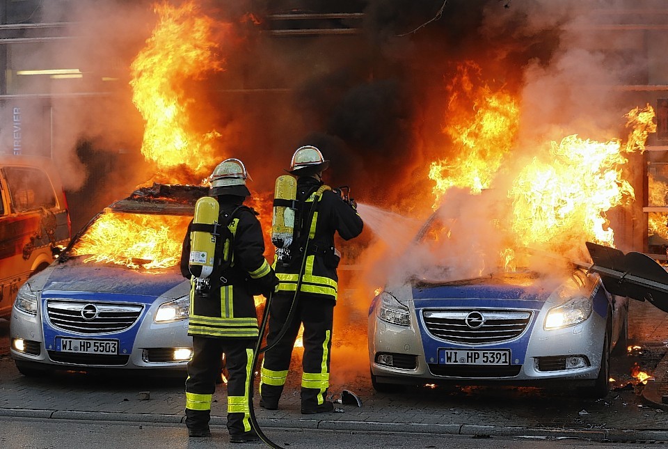 Firefighters extinguish flames in burning police cars 