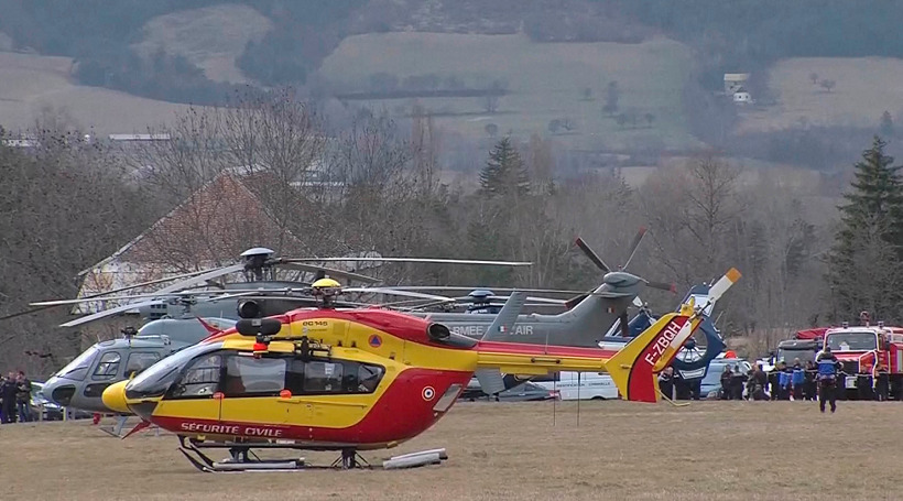 A red and yellow helicopter seen at the base of rescue operations, similar to the one pictured flying over the debris on the French mountainside