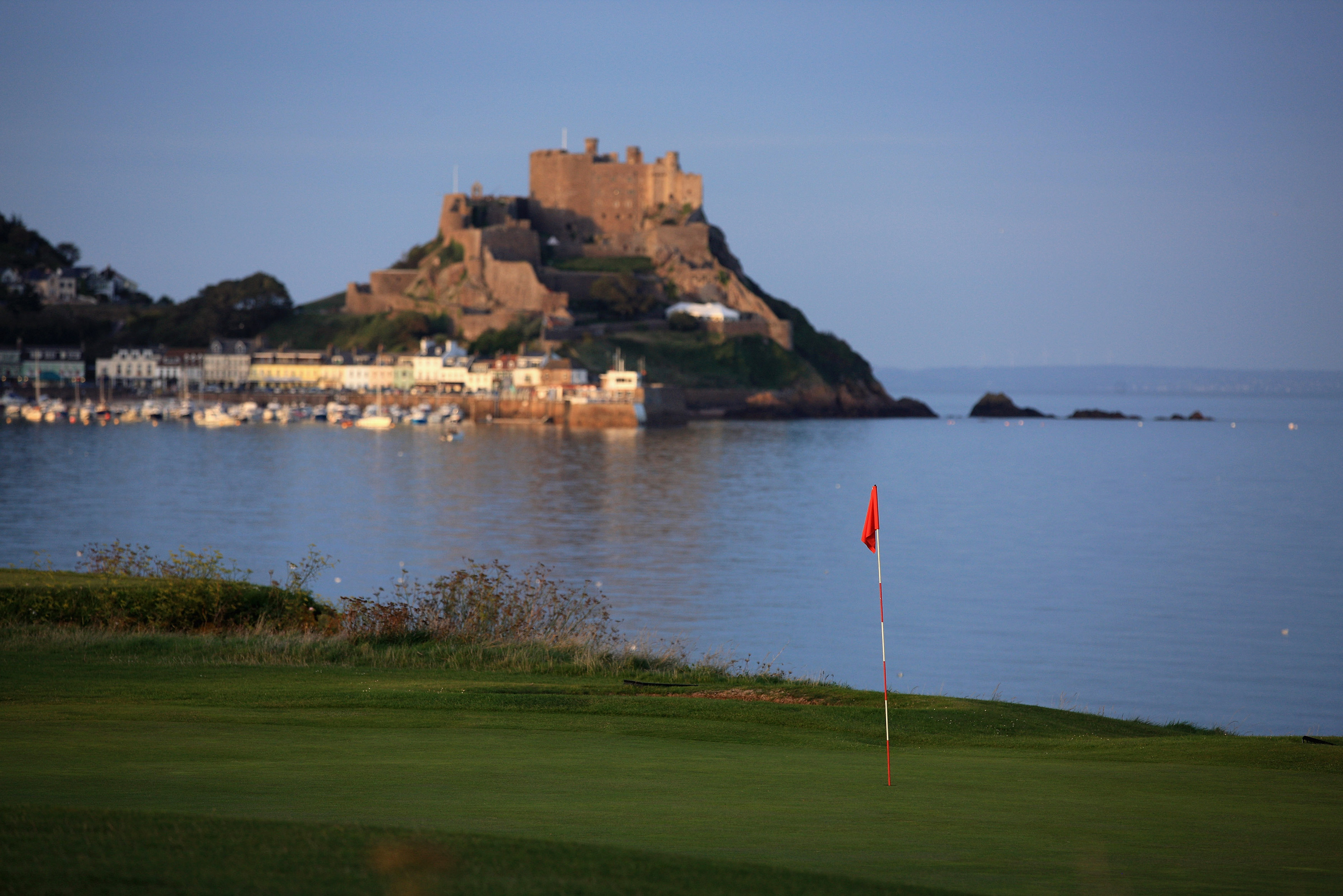 A view of the green on the 470 yards par 5, 1st hole accross the bay to The Mont Orgueil Castle and the village of Gorey, at The Royal Jersey Golf Club