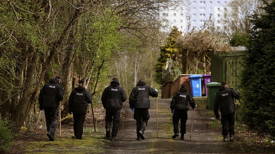 Police search garages and the surrounding areas near a block of flats in Dorchester Avenue