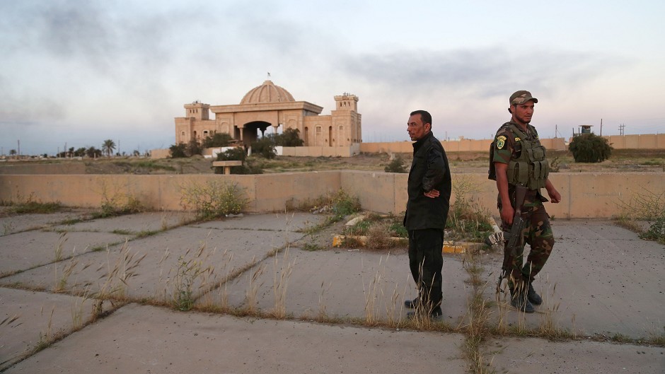 Iraqi security forces and allied Shiite militiamen stand guard in front of one of Saddam Hussein's palaces in Tikrit (AP)