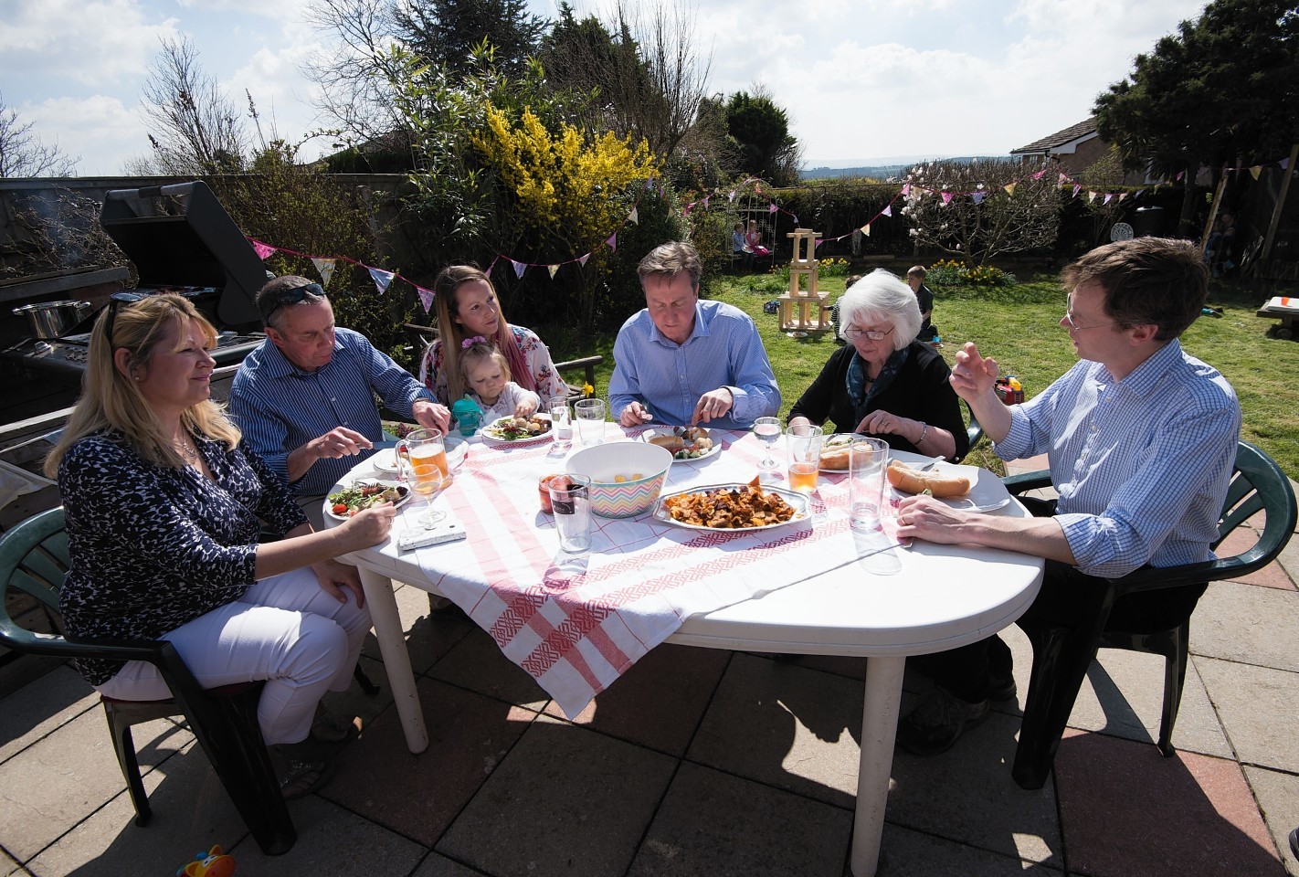 Prime Minister David Cameron eats lunch in a garden with the Docherty family from Poole, Dorset, during a visit to the westcountry, as part of his 2015 general election campaign. 