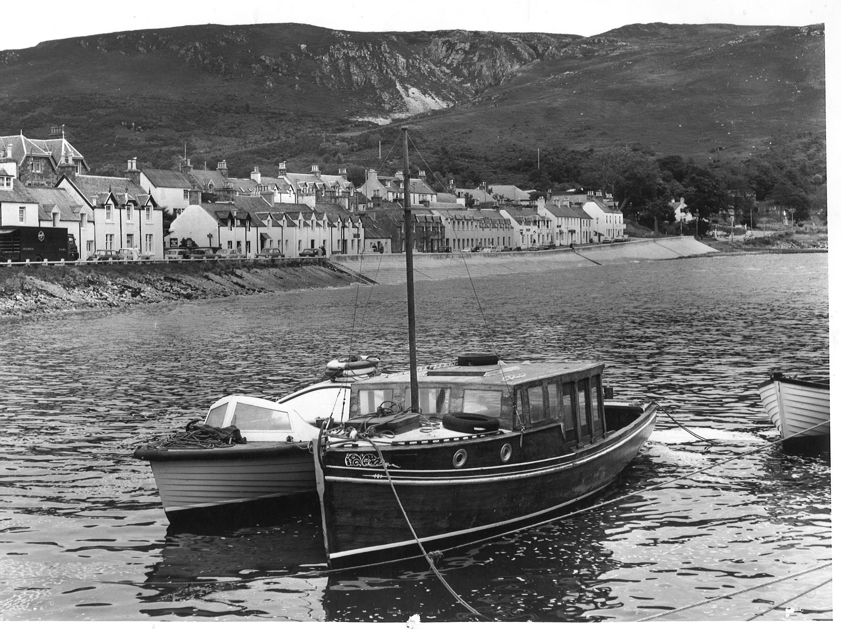 Pleasure boats ride at anchor in the quiet waters of Loch Broom with Shore Street in the background.